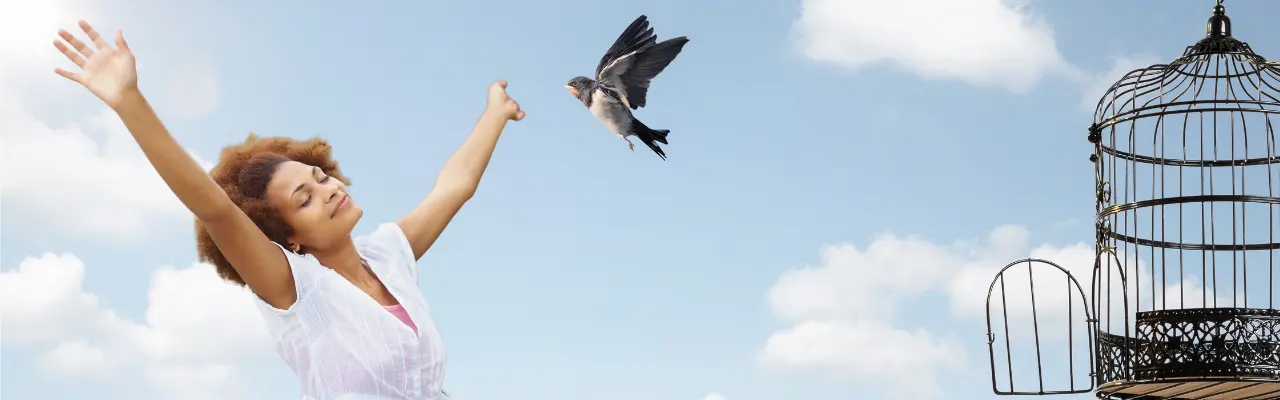 Femme épanouie les bras ouverts et oiseau s'envolant d'une cage, symbolisant la libération émotionnelle et l'éveil des potentiels.